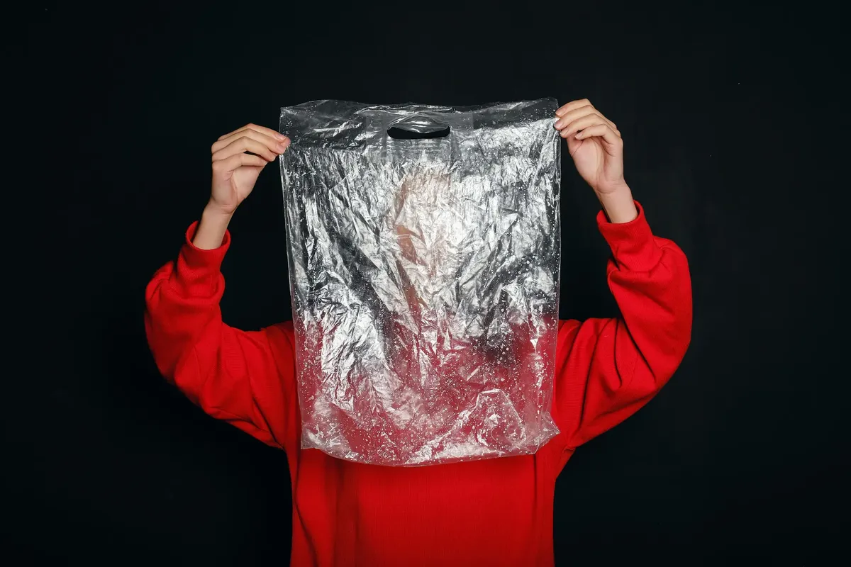 Conceptual image of a person holding a clear plastic bag, symbolizing pollution and recycling themes.