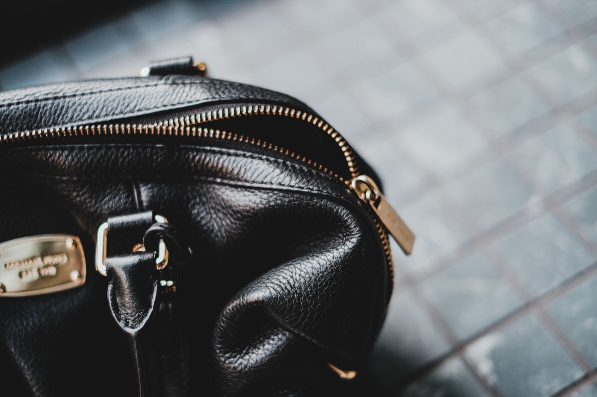 Detailed view of a high-end gold metal clasp on a designer leather bag.